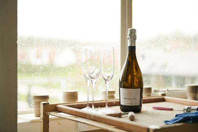 Prosecco bottle on a wooden board with three glasses