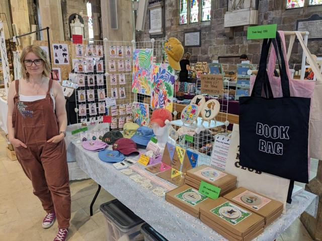 image of artist next to a market stall stand