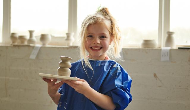 Child holding pot from Potter's Wheel