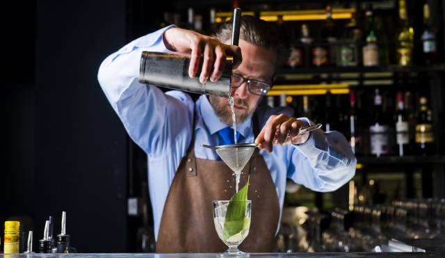 Bartender behind the Lunar bar making a cocktail