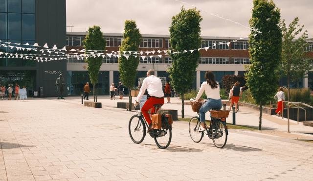 Two people riding bikes in the Wedgwood courtyard