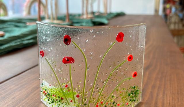 Glass ornament with red poppy design and green foliage 