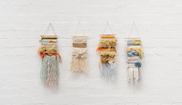 Four hand woven tapestry's on a white walled background
