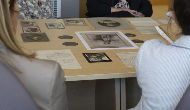 Image of table with people sitting around. On the table is archive materials from Wedgwood Collection.