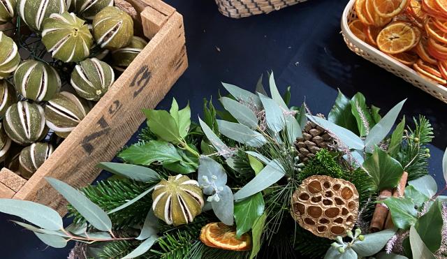 Table with Christmas wreath and dried oranges and limes in baskets