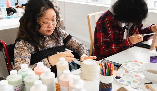 Lady sat at a table painting a pot